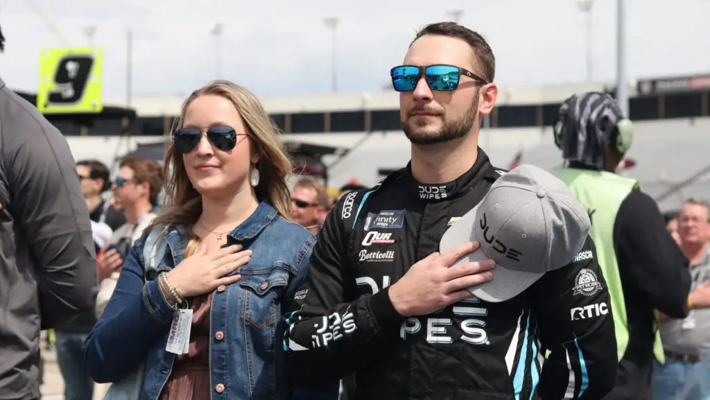 Anthony Alfredo stands next to his partner with their hands on their heart ahead of the NASCAR Xfinity Series race at Marinsville.