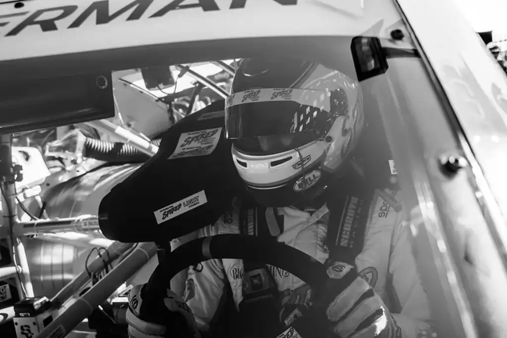 A black and white photo of Parker Kligerman inside his race car.