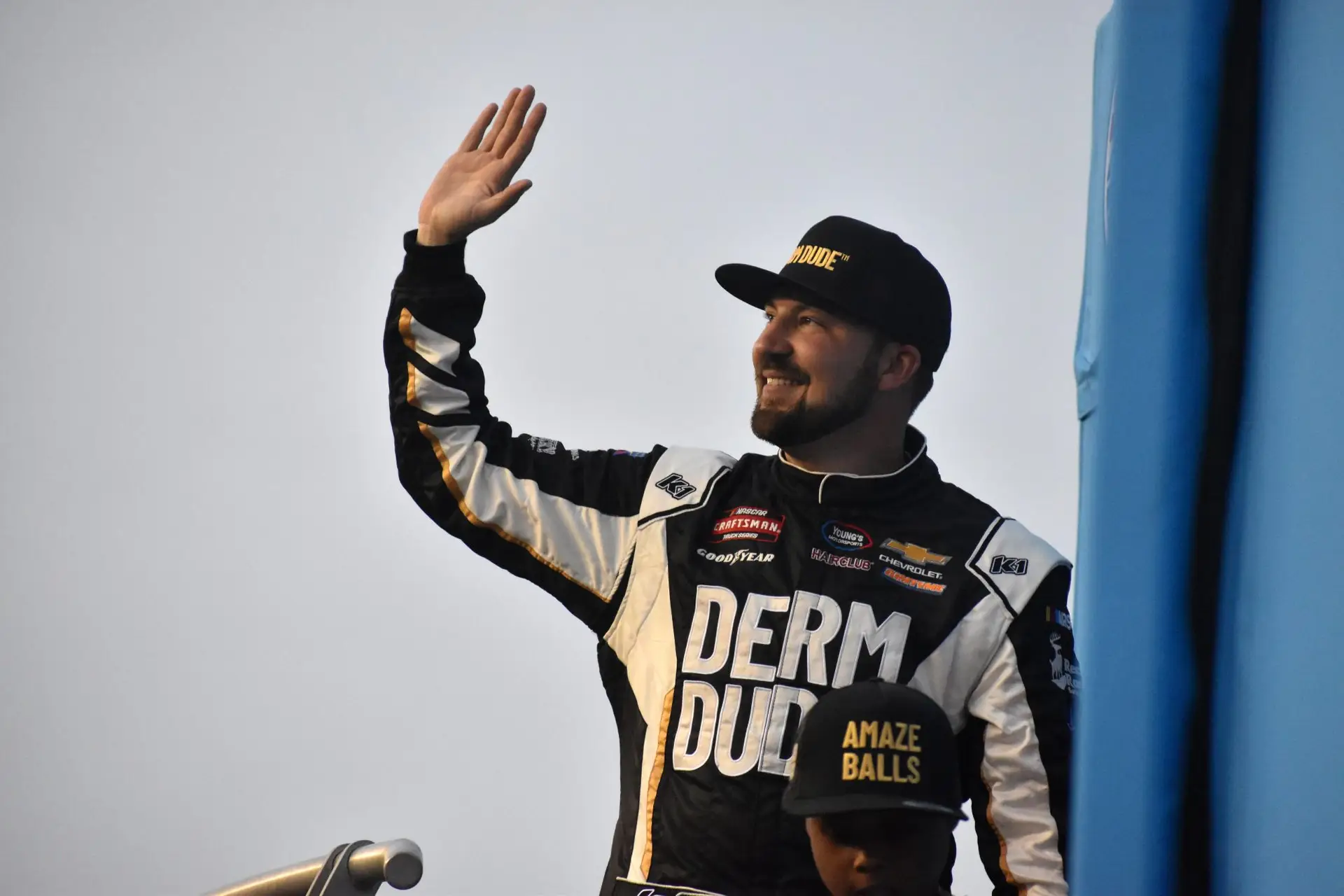 Spencer Boyd in a black and white Derm Dude fire suit waving to the crowd during driver intros.