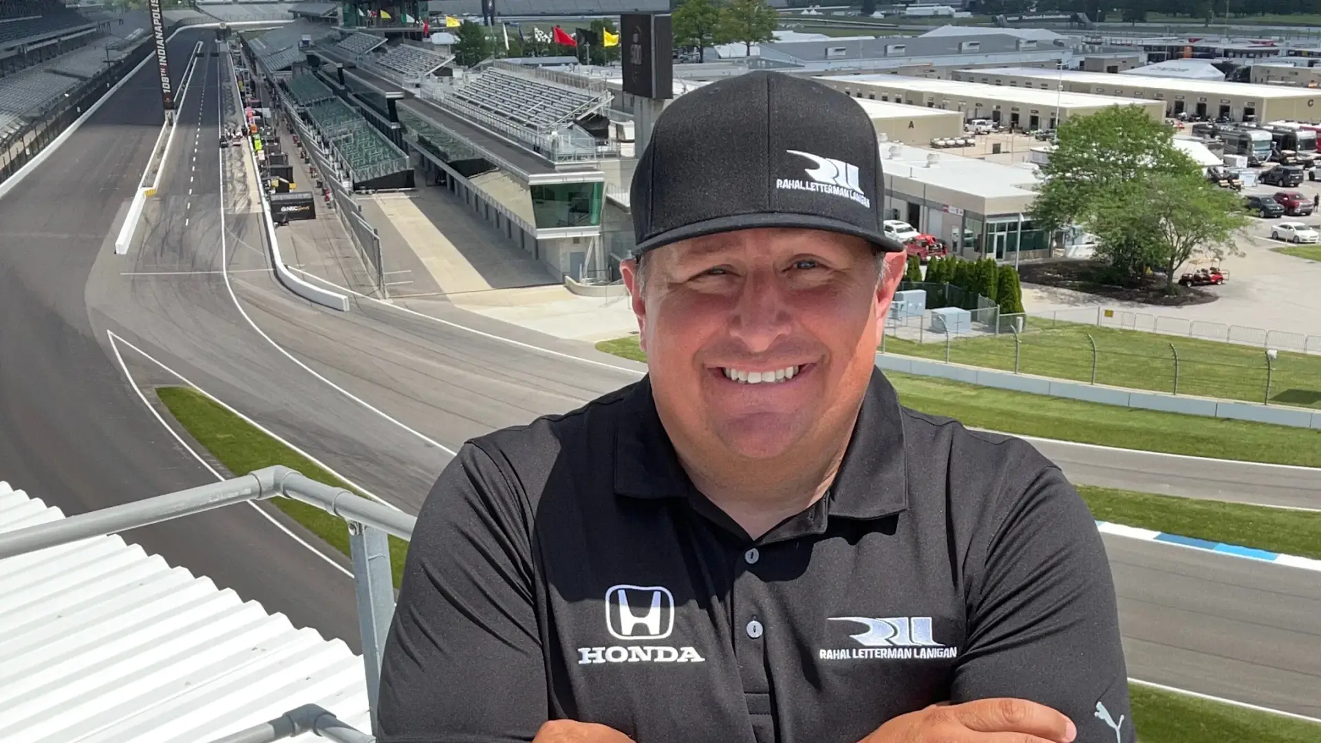 Brent Wentz stands in the stands at Indianapolis Motor Speedway in a black Honda polo.