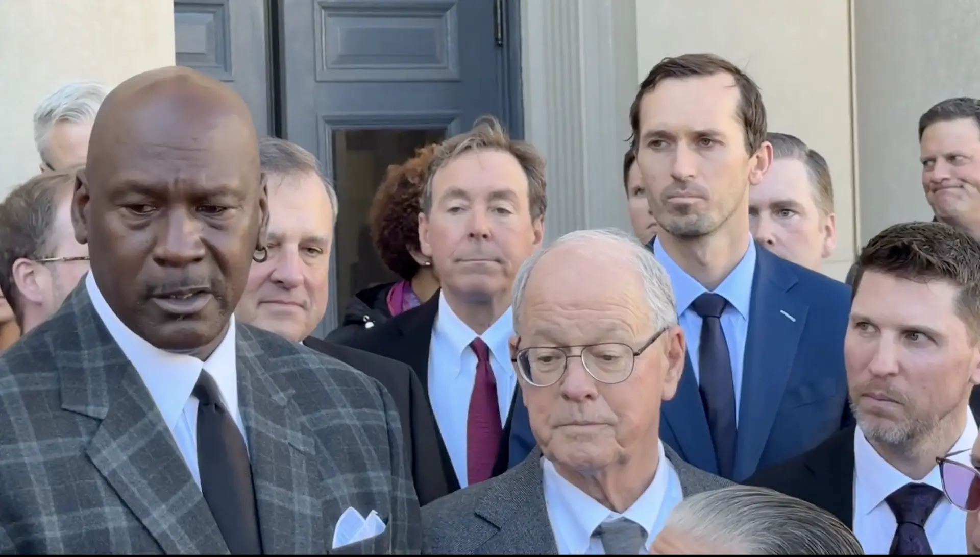Michael Jordan, Jim France, and Denny Hamlin stand in front of a North Carolina courthouse after the federal antitrust lawsuit was settled ahead of Day 9 of the trial.