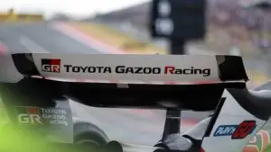 The wing of an open-wheeled car what is white with black text saying "Toyota Gazoo Racing" on the race track.